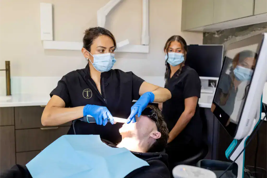 A masked clinician carrying out an intraoral scan on a patient