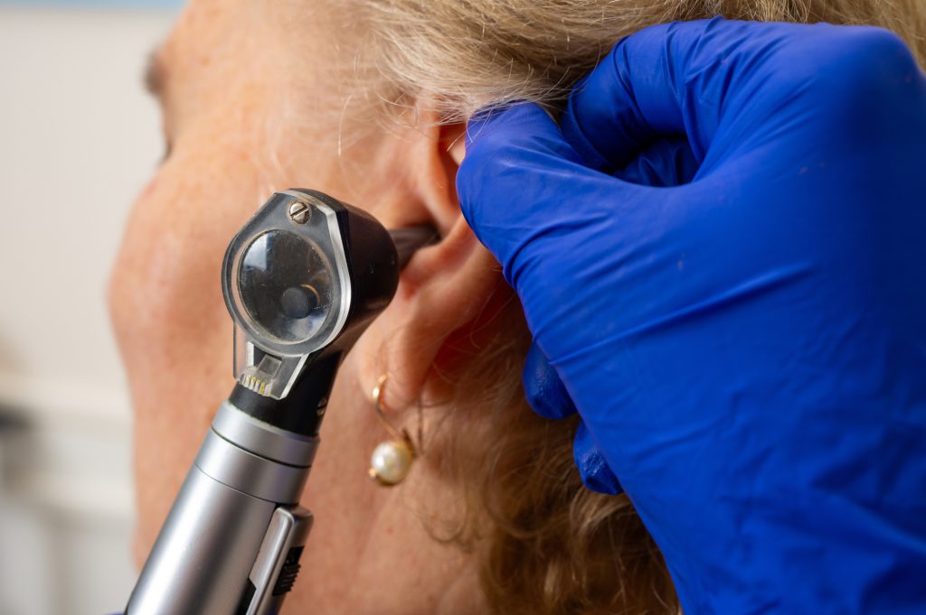 A clinician examining a patient's ear with an otoscope