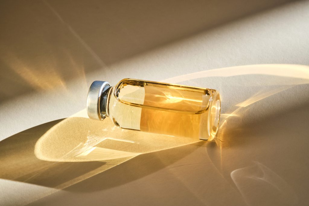 A glass vial of vitamin solution in warm light