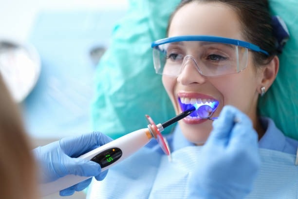 A dentist curing composite bonding with a blue light