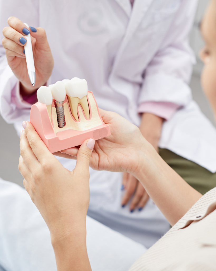 A clinician pointing to a dental implant on a tooth model