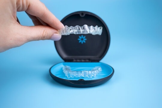 A clear aligner being lifted from its case