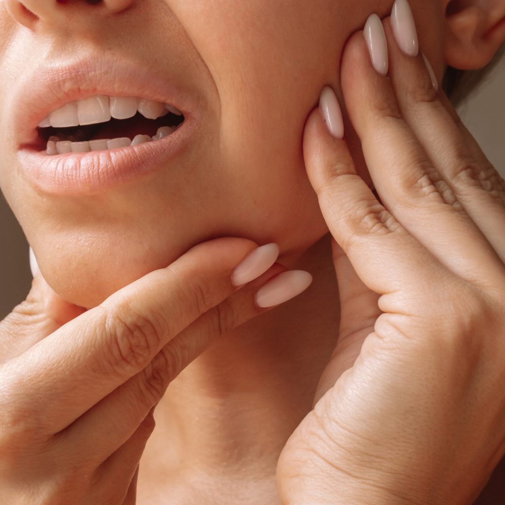 A woman holding her jaw with both hands, showing jaw joint pain